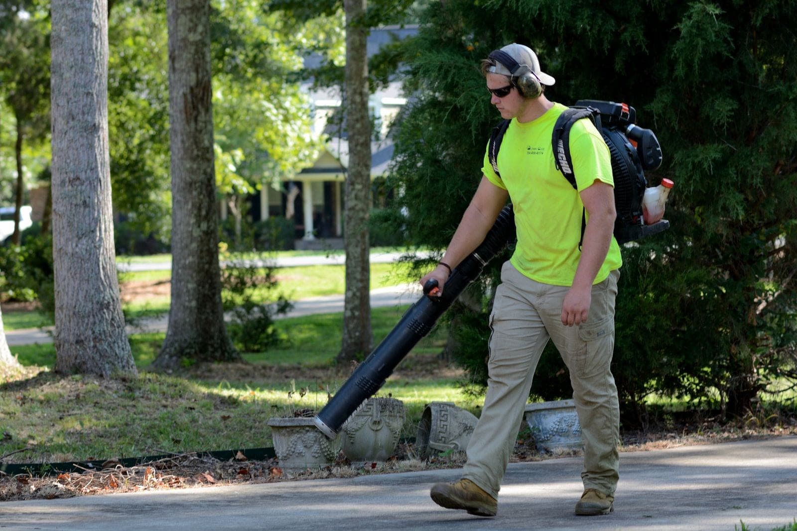 Crew member clearing debris with a leaf blower after a tree removal