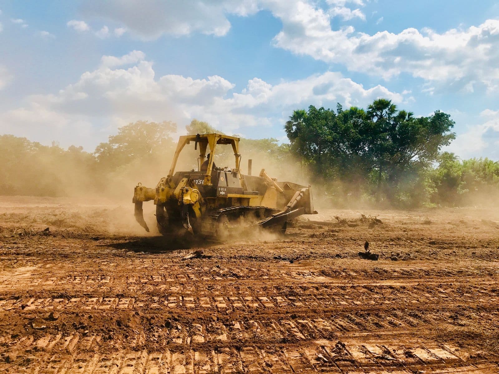 Bulldozer clearing a dusty lot