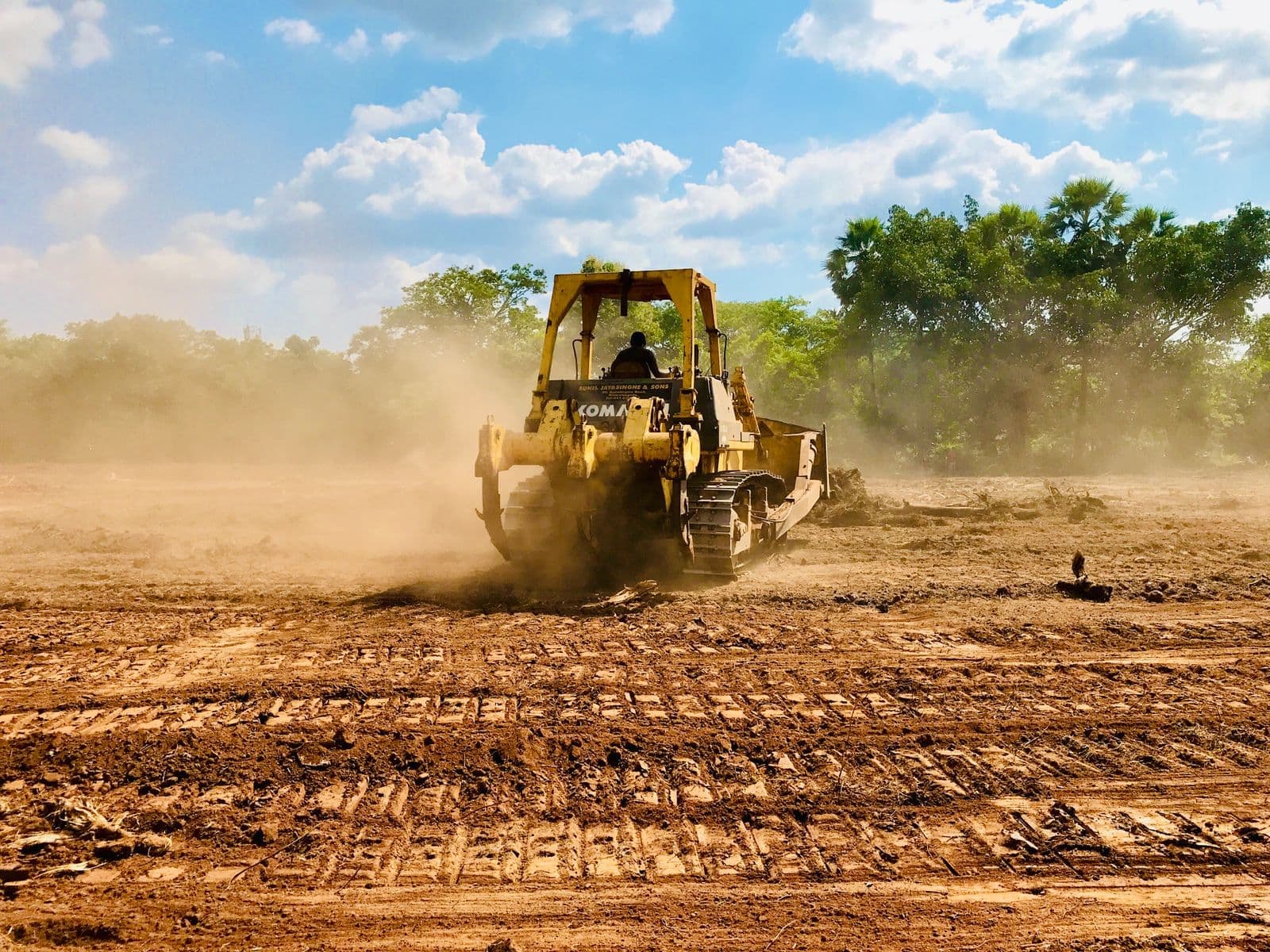 Bulldozer clearing a dusty lot